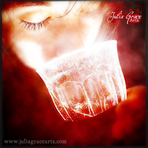 A red-hued photograph of girl drinking a mysterious bright red liquid from a glowing glass