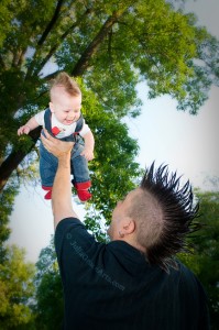Father holding baby up in the sky with mohawks